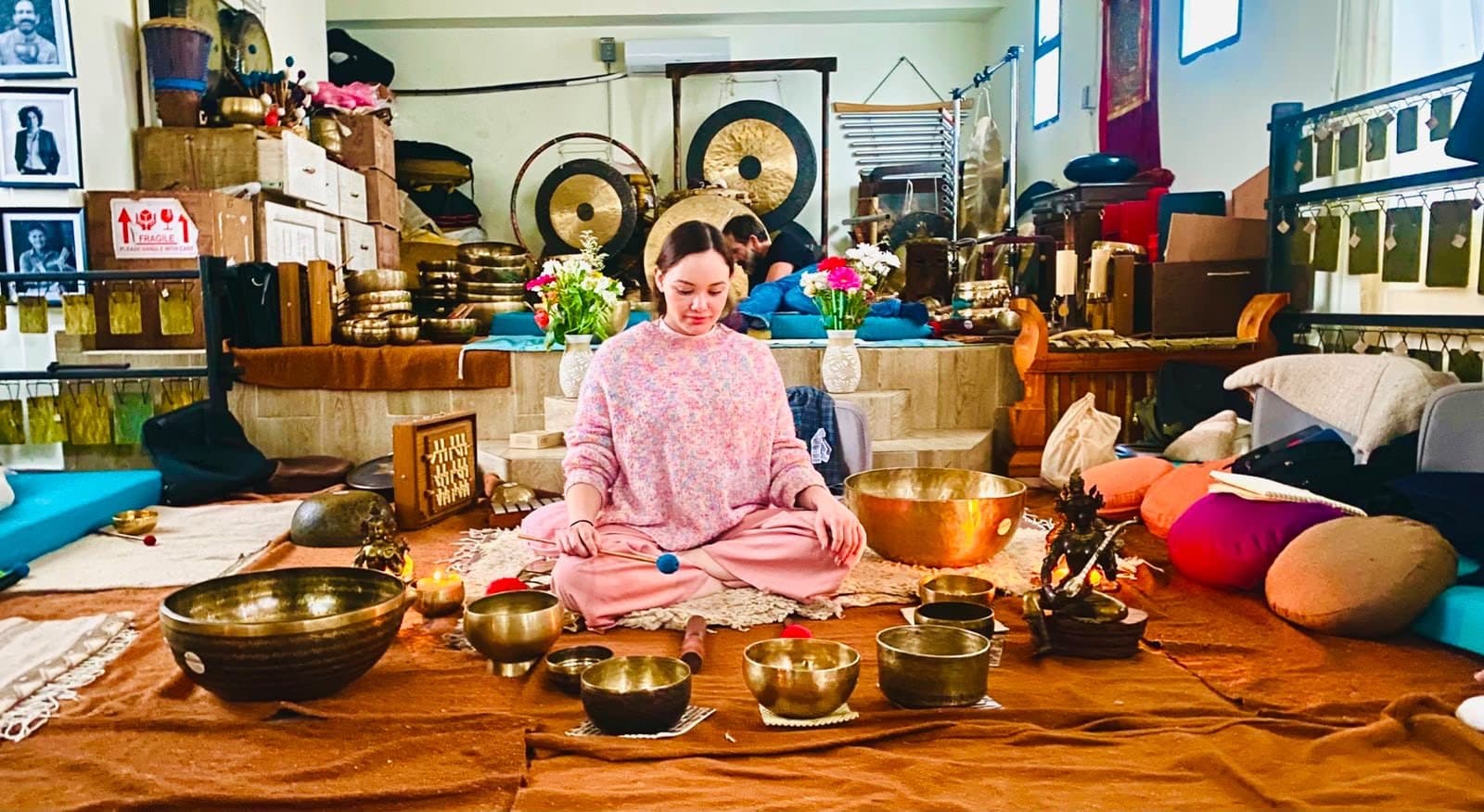 Erika sentada en el piso rodeada de instrumentos: gongs colgados, decenas de cuencos de metal de todos los tamaños, cojines y velas.